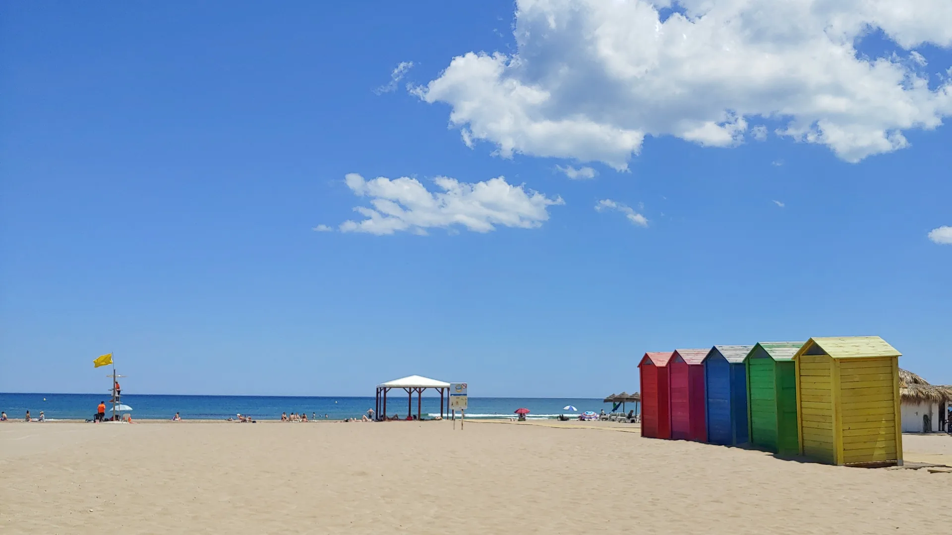 Wide sandy Patacona Beach with colourful beach huts and the Mediterranean Sea